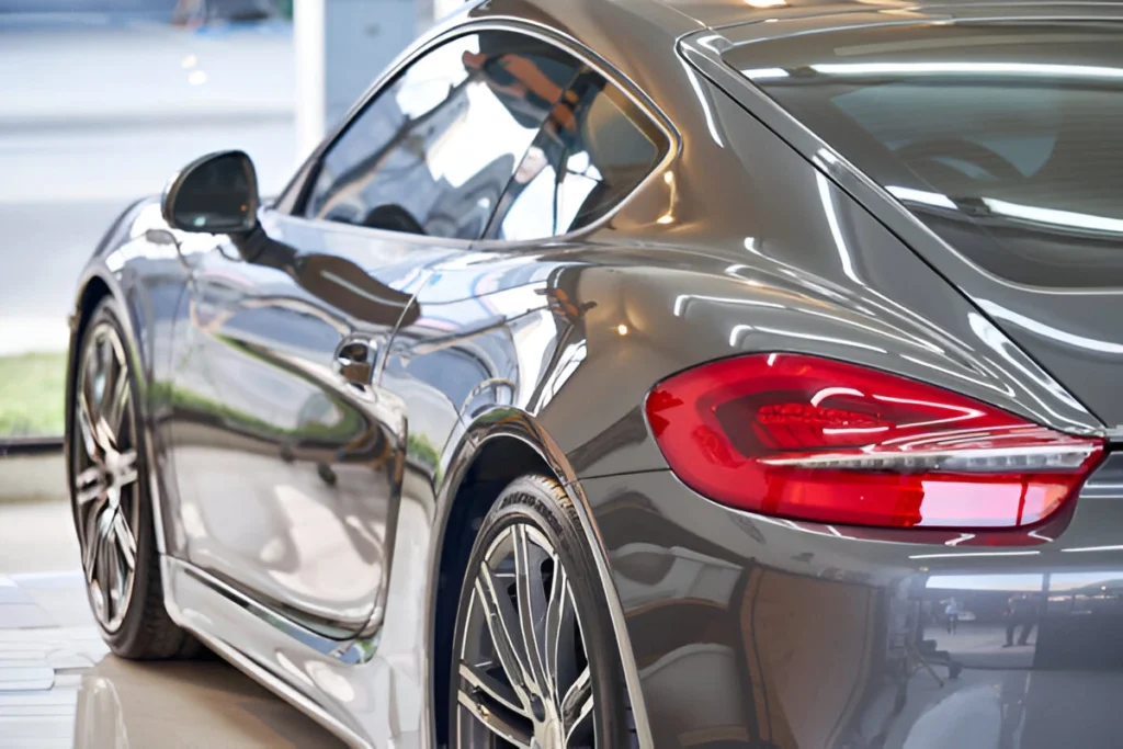 Sleek silver sports car with a highly reflective paint or wrap finish, showing clear reflections of the surrounding environment and lighting.