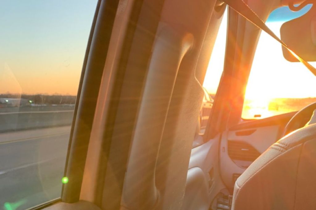 View from inside a car at sunset, with harsh sunlight beaming through untinted windows, creating intense glare and discomfort. This image visually represents what is window tinting designed to prevent—excessive heat, UV exposure, and reduced visibility for Colorado drivers.