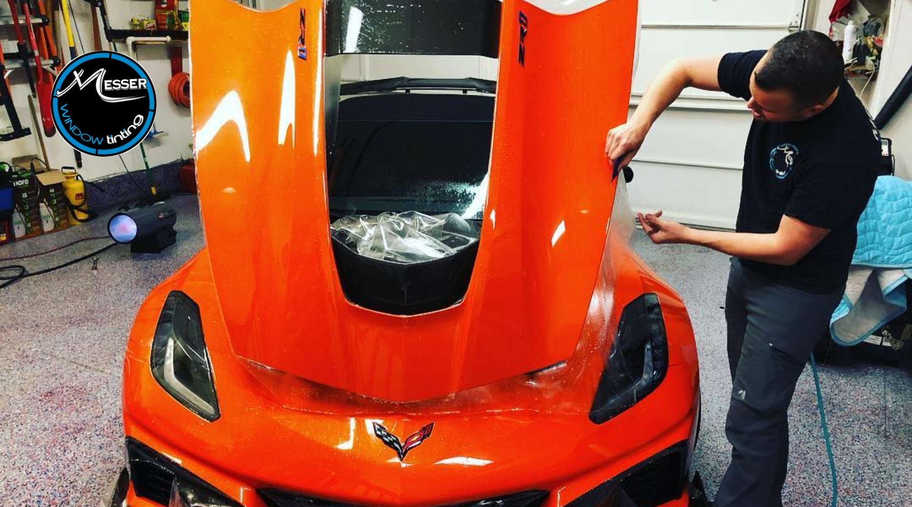 Technician applying paint protection film to an orange Corvette in a Parker, Colorado garage – Benefits of Paint Protection Film for protecting high-end vehicles from local road wear.