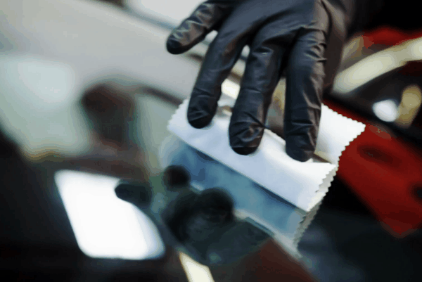 Technician applying ceramic coating to a car surface using an applicator pad during paint protection treatment